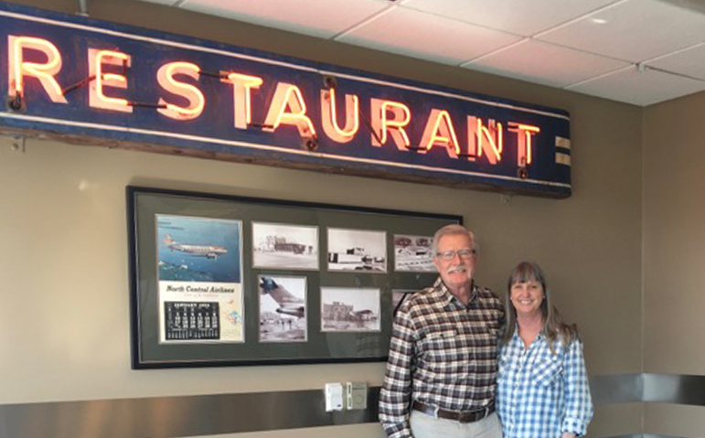 Jet Room owners Pat and Pam O’Malley in front of the 1950s restaurant sign that originally hung outside the airport terminal building.