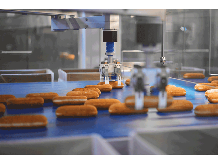 Robotic arms lift and place Long Johns, and other bakery treats, into boxes for distribution.
