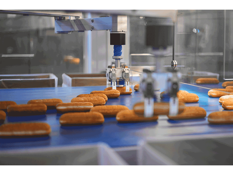 Robotic arms lift and place Long Johns, and other bakery treats, into boxes for distribution.