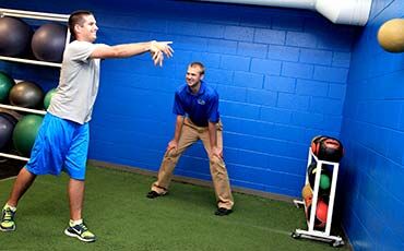 Kane Sivesind of CORE Health & Fitness looks on as one of his clients tosses a medicine ball.