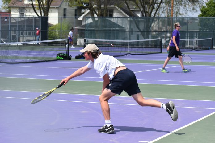 Madison East High School’s Isaiah Loeb fires a serve during a match on the Purgolders’ home court.