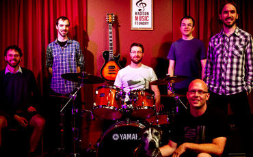 The Madison Music Foundry staff, including owner Michael Olson (kneeling), is dedicated to local music education.