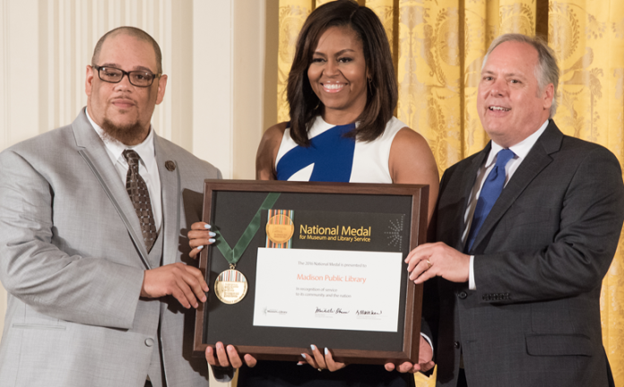 Library Director Greg Mickells (right) accepts the National Medal for Museum and Library Service on behalf of the Madison Public Library June 1 from First Lady Michelle Obama at the White House. Mickells was joined by community member Rob Franklin (left), known locally as Rob Dz.