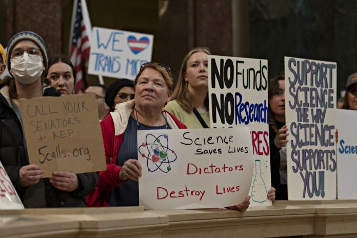 Participants shared signs at the State Capitol Rotunda during the Stand Up For Science rally March 7.