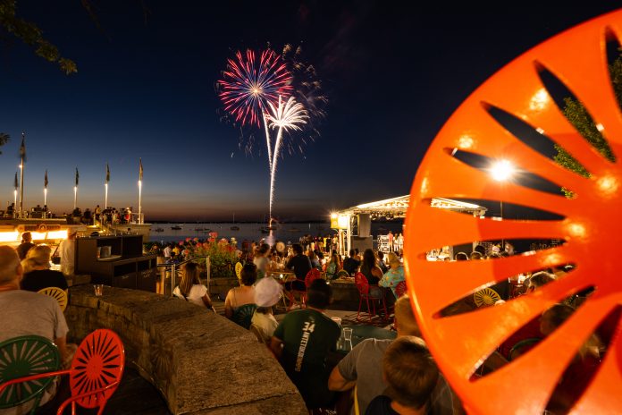 Members of the UW–Madison community enjoy a summer night on the Terrace as a fireworks show takes place over Lake Mendota during the 175th Anniversary Launch Day Celebration at the Memorial Union Terrace during summer on July 26, 2023. The event is the start of a year-long demisemiseptcentennial celebration of the July 26, 1848 creation of the University of Wisconsin. (Photo by Jeff Miller / UW–Madison)