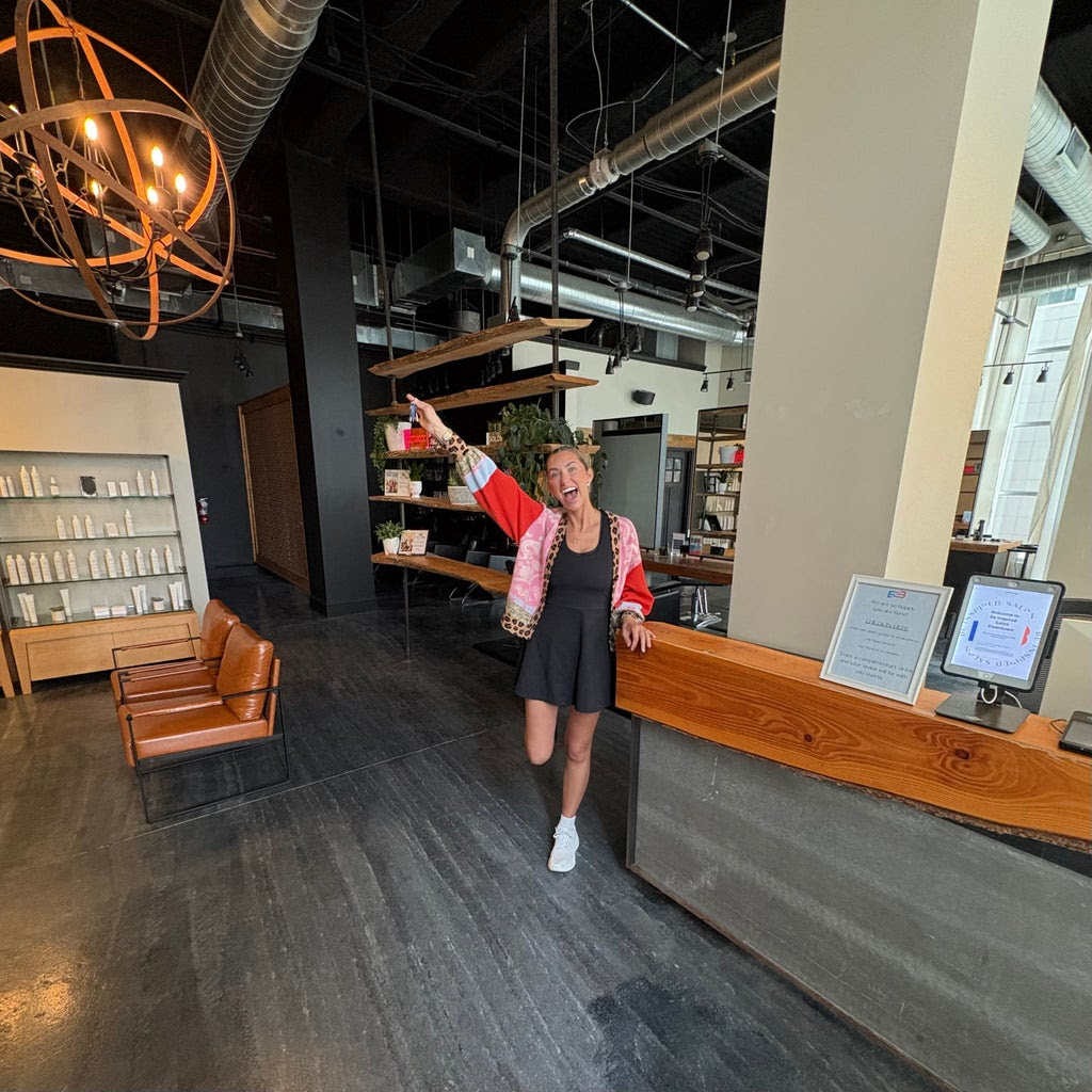 Hannah Schatschneider cheers inside a salon after becoming the new owner.