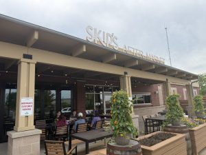 A group of people sits at a table outside of restaurant Skip's Market.