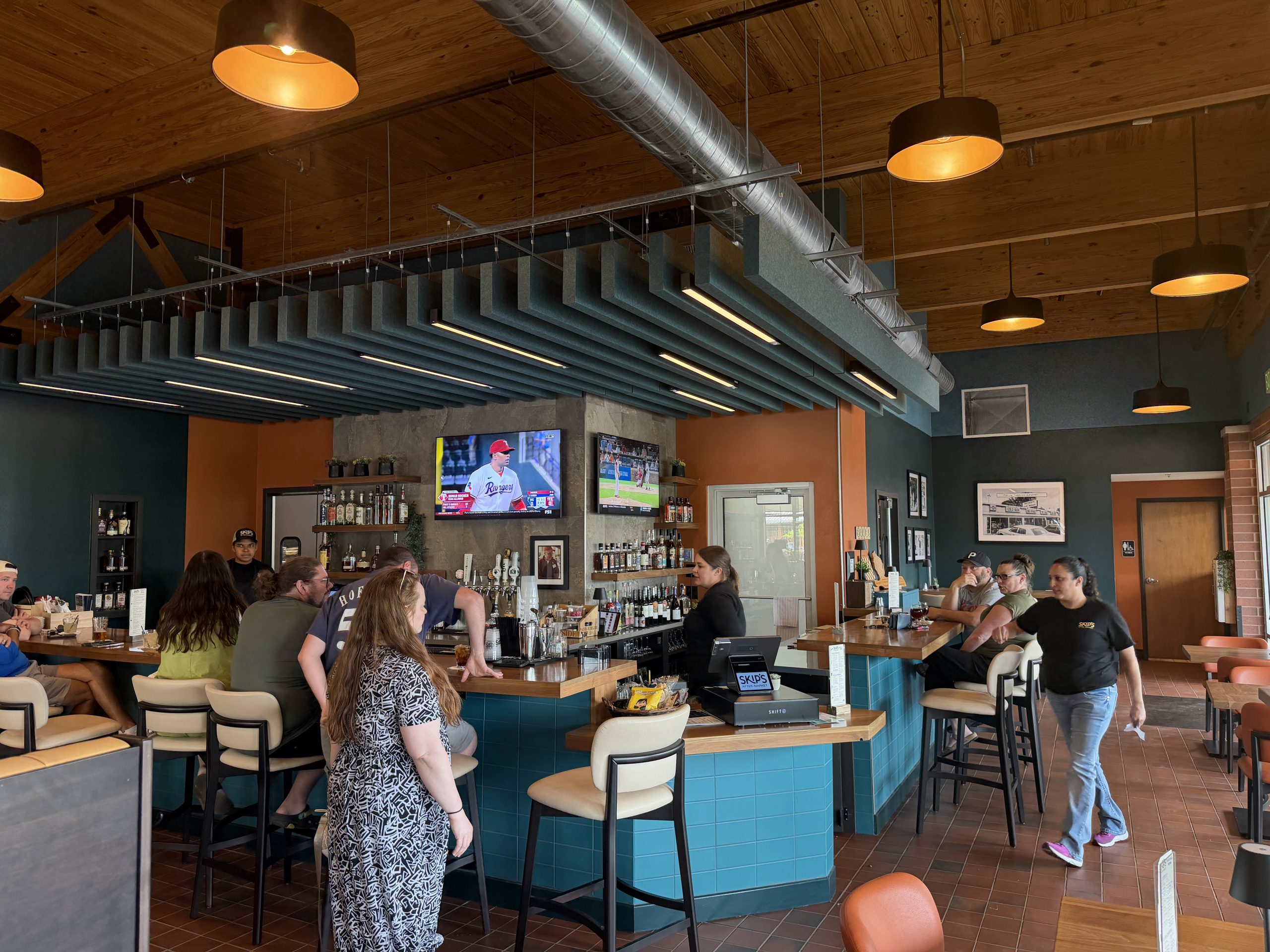 People walk around and sit in a bar and restaurant named Skip's Market, a part of Brennan's Market.