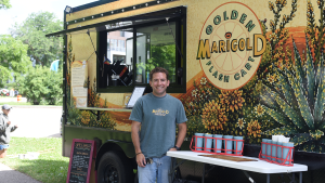 Clark Heine stands next to Marigold Golden Flash Cart at Brittingham Boats on Lake Monona. At right are pastries available at the cart.