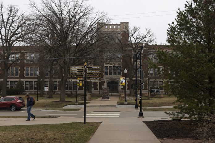 A person walks across campus on an overcast day at the University of Wisconsin-Oshkosh on March 31, 2026, in Oshkosh, Wis. Nearly half of UW-Oshkosh’s student enrollment comes from high schoolers taking college courses. (Joe Timmerman / Wisconsin Watch)
