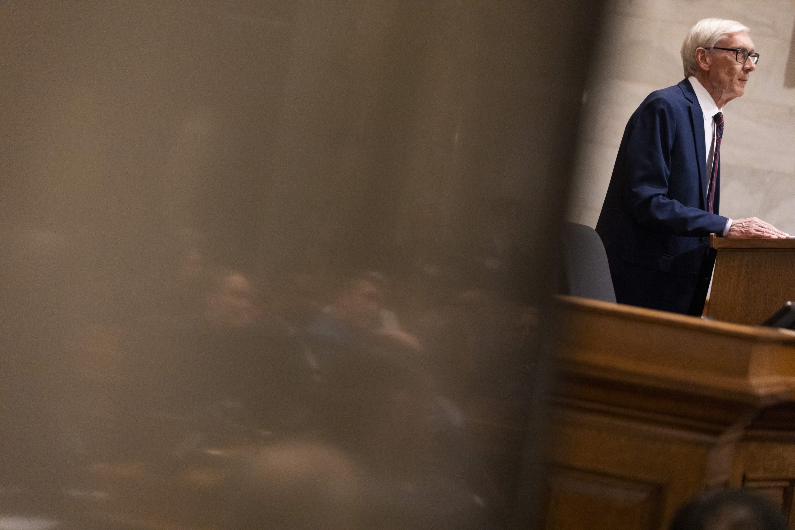 Lawmakers are reflected in the marble wall as Wisconsin Gov. Tony Evers delivers his final State of the State address at the Wisconsin State Capitol on Feb. 17, 2026, in Madison, Wis. (Joe Timmerman / Wisconsin Watch)