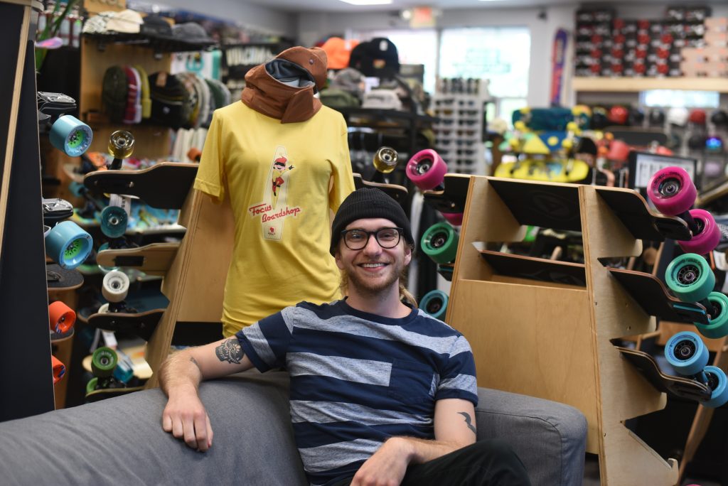 A man in a striped shirt sits on a couch in Broken Board Coffee. 
