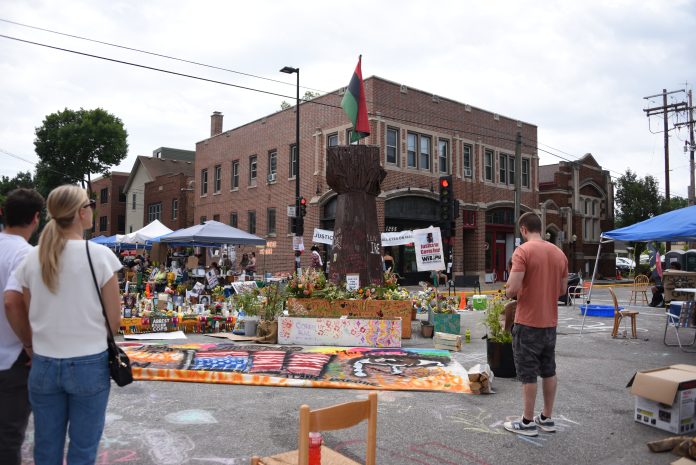 Corey Ruiz memorial with people, candles, art and a giant black fist