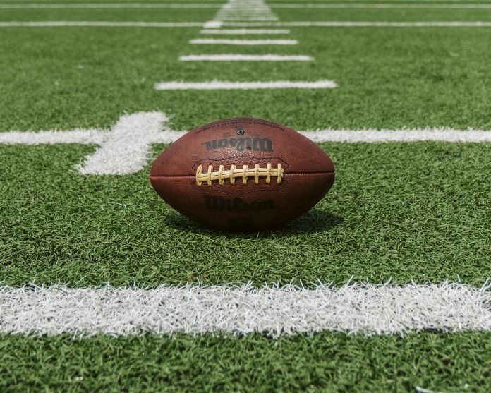 An American football on a turf field with white lines