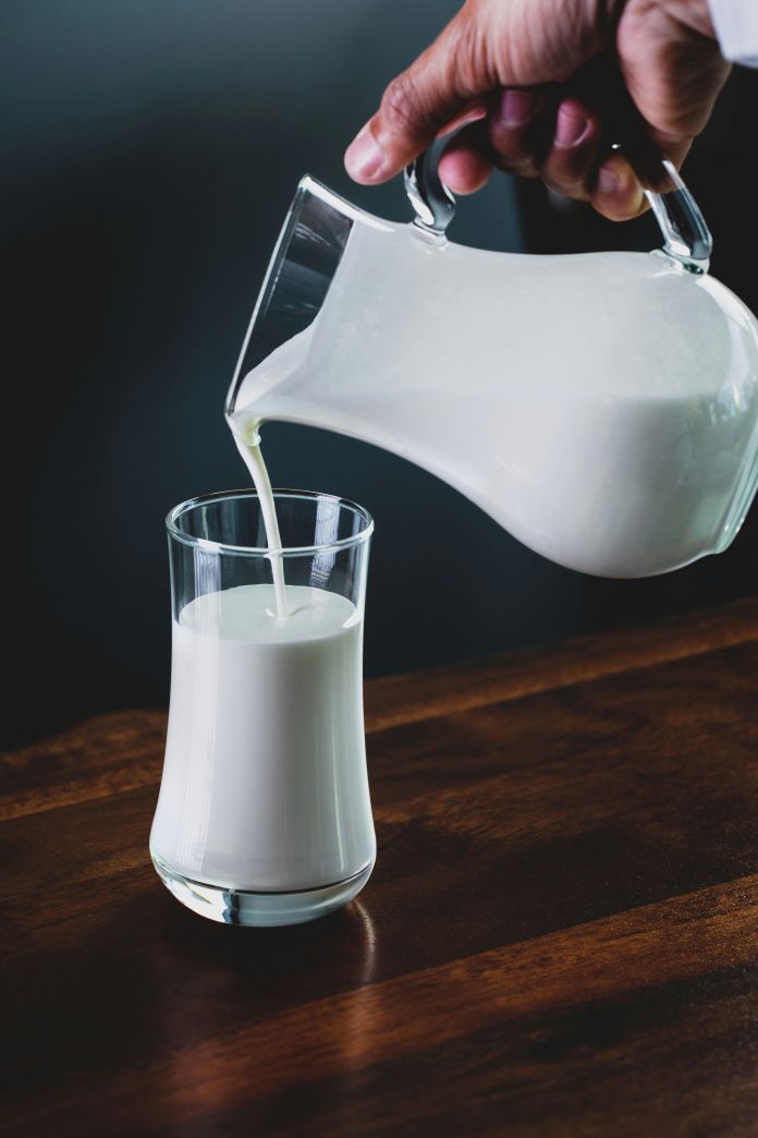 Pouring milk into a glass from a glass tankard