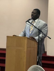 A man stands at a podium and speaks into a microphone. 