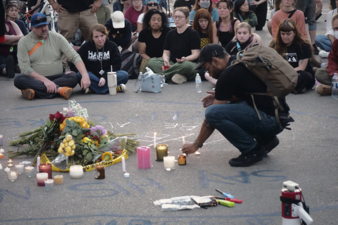 A man lights a candle on a city street