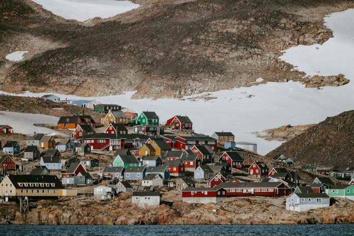 An array of colorful houses on a bland rock with snow in Greenland