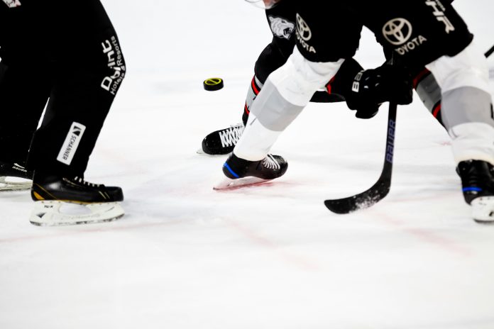The feet of two hockey players and a referee
