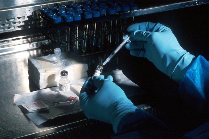 Someone wearing latex gloves to test a liquid